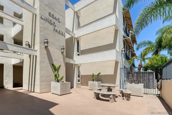 Outdoor view of a multi-story building with beige walls displaying an address and name.