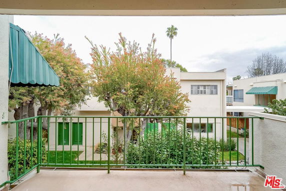 View from a balcony overlooking a residential area with trees and buildings.