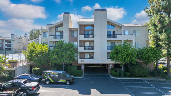 Front view of a multi-story residential building with balconies and parking area.