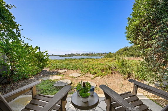 View of natural landscape and water body from a patio with chairs.
