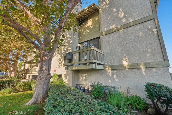 Side view of a multi-story residential building with balconies and beige exterior walls.