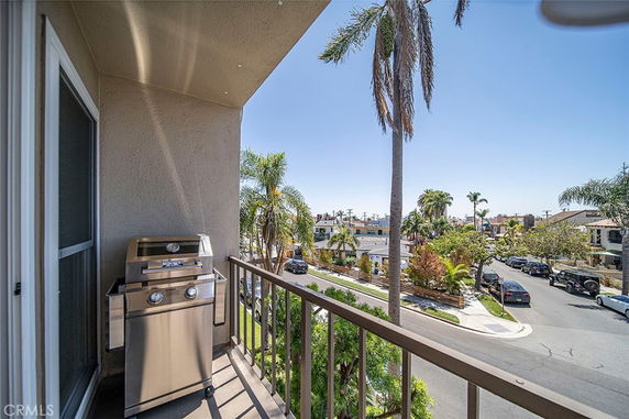 View from a balcony showing a street lined with palm trees and residential houses.