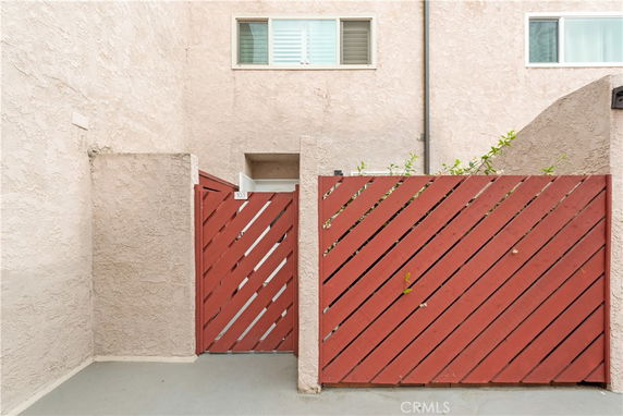 Front view of a building entrance with red diagonal wooden fencing and a small window above.