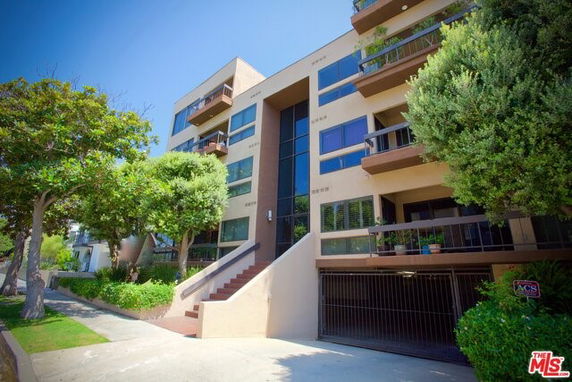 Front view of a multi-story apartment building with balconies and a garage entrance.