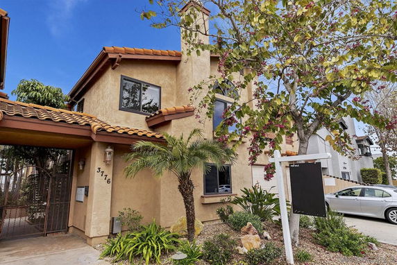 Front view of a two-story house with a tiled roof and stucco exterior.