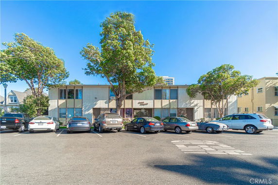 Parking area in front of a two-story building with trees around.