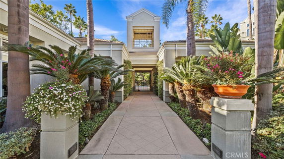 Elevated entrance of a building surrounded by palm trees and greenery.