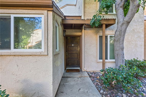 Front view of a two-story house with a brown wooden door and surrounding windows.