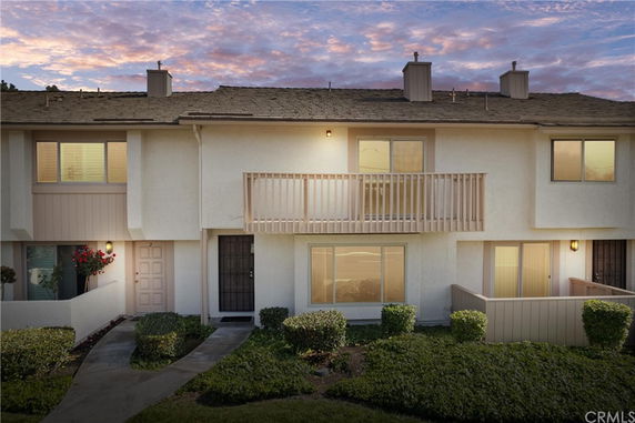 Front view of a two-story house with a balcony and front entryway.