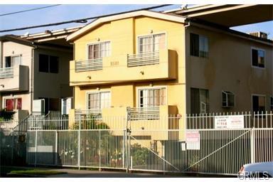 Front view of a multi-story building with balconies and a gated entrance.