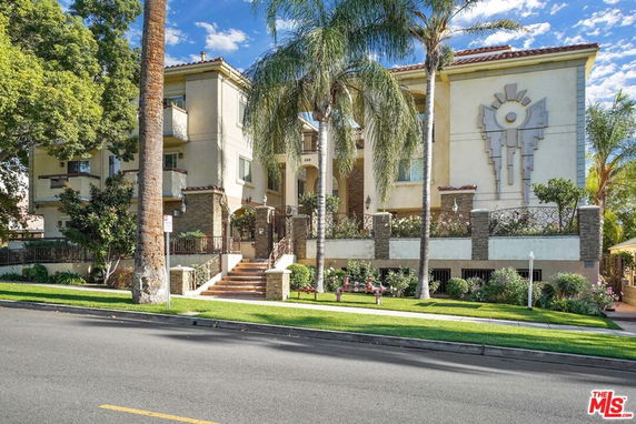 Front view of a multi-story building with architectural details and palm trees.
