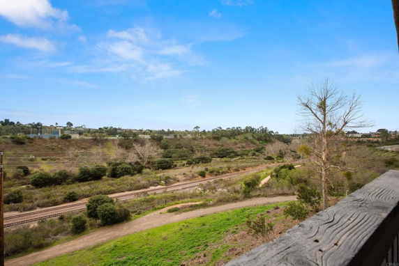 View of grassy landscape with train tracks and hills in the distance.