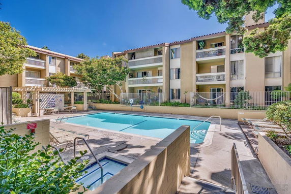 Outdoor swimming pool area in front of a multi-story apartment building.
