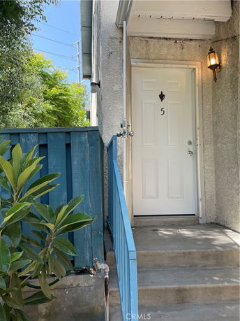 Front entrance of a building with a blue railing and a white door labeled with the number 5.
