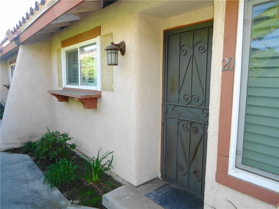 Front view of a house with a decorative metal door and a window with a small ledge.