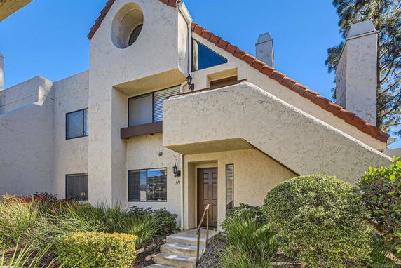 Front view of a multi-story apartment building with a staircase and a circular window design.
