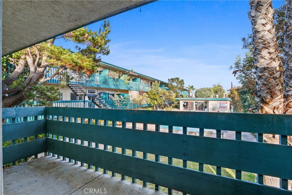 View from a balcony overlooking a multi-story building with external staircases and outdoor pool.