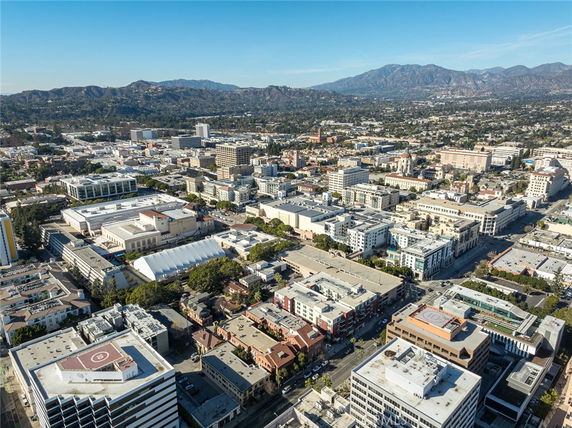 Aerial panoramic view of a cityscape with numerous buildings and distant mountains.