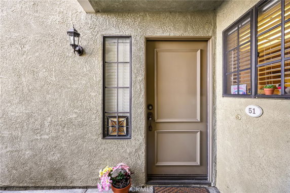 Front view of a residential entrance with a beige door and surrounding windows.