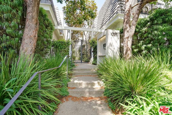 Entrance view of a residential building with gated access and surrounding greenery.