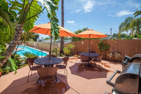 Outdoor swimming pool area with tables and umbrellas.