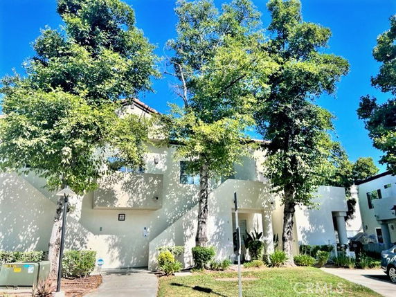 Front view of a multi-story residential building with staircases and surrounding trees.
