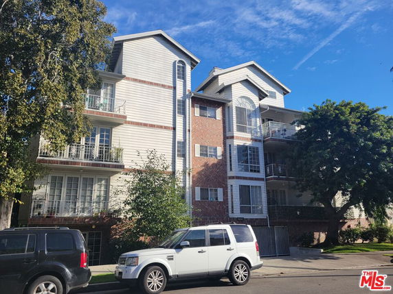 Front view of a multi-story residential building with balconies and a brick facade.