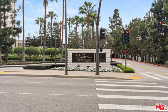 Front view of a building entrance with a sign and landscaped garden.