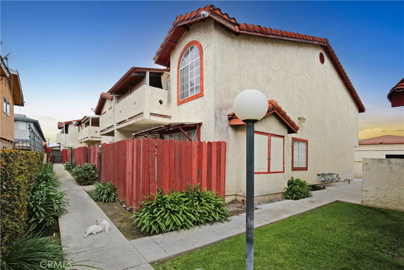 Exterior view of a two-story house with red roof tiles and a red fence.