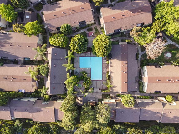 Aerial view of a residential area with multiple buildings surrounding a central swimming pool.