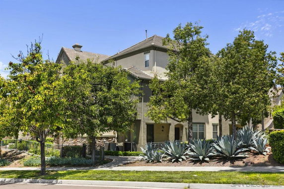 Front view of a two-story residential building with a sloped roof and surrounding trees.