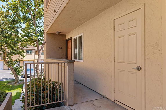 Front view of a residential building entrance with a small porch and railing.