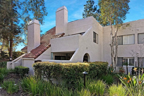 Front view of a two-story house with white stucco walls and a red-tiled roof.