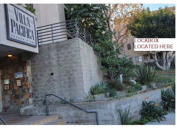 Exterior view of a condominium building entrance with sign 'Villa Pacifica'.