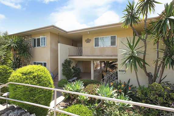 Front view of a two-story residential building with a balcony and entrance walkway.