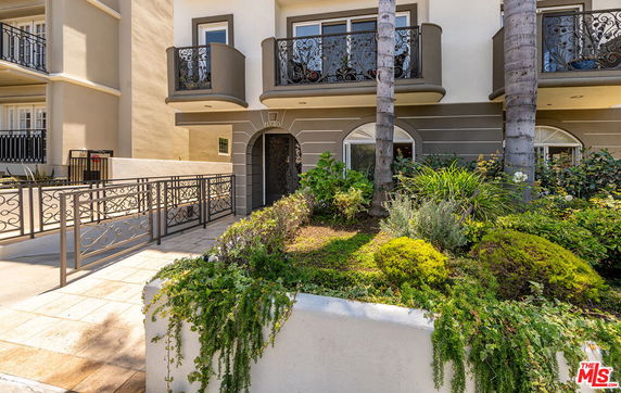 Front view of a residential building with balcony railings and garden.