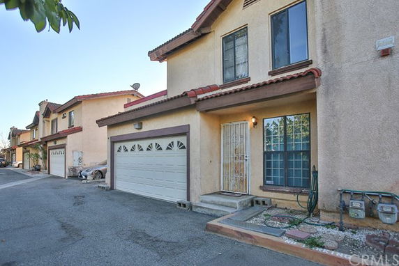 Front view of a two-story house with a garage and a gated entrance.