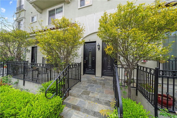 Front view of a multi-story townhouse with a black door and decorative railing.