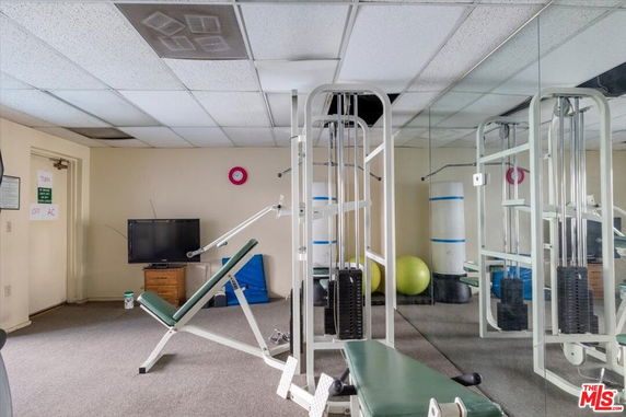 Indoor gym area with exercise equipment and mirrored wall.