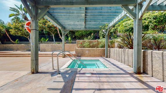 Outdoor area with a small swimming pool under a pergola.