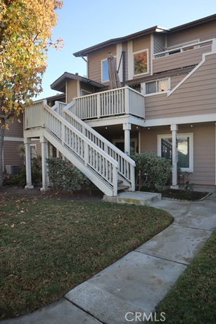 Front view of a two-story house with an exterior staircase and balcony.