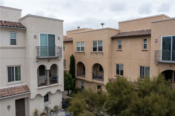 Front view of a multi-story residential building with balconies and arched entrances.