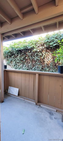 Outdoor covered area with wooden railing and plants.