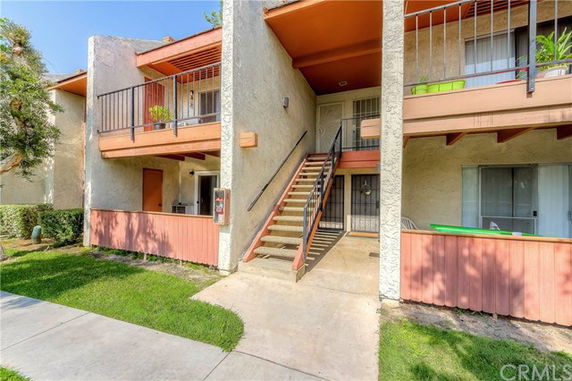 Front view of a multi-story apartment building with exterior staircases and balconies.