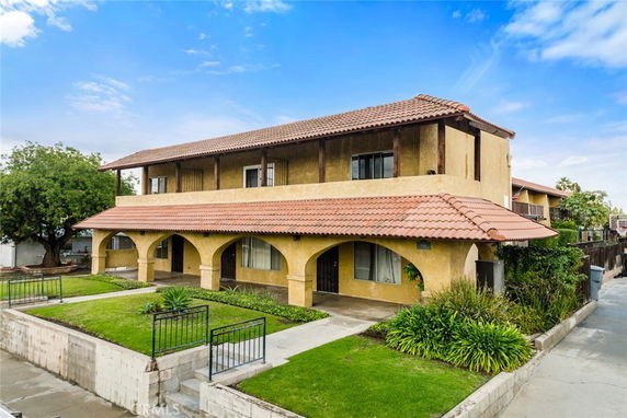 Front view of a two-story house with a tiled roof and arched entryways.