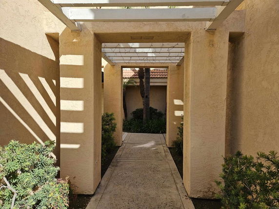Front view of a building with a walkway covered by a pergola.
