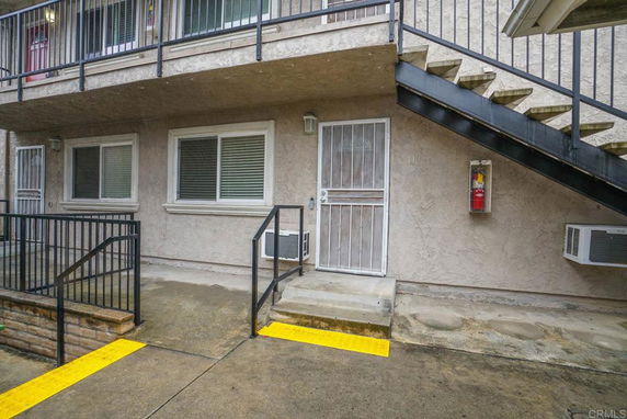 Front view of a multi-story building with external staircase and railings.