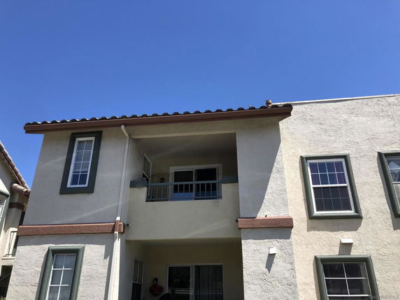 Front view of a two-story house with a balcony and multiple windows.