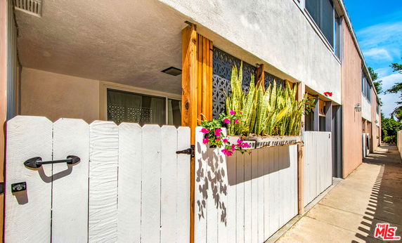 Front view of a residential building with white gate and plants.