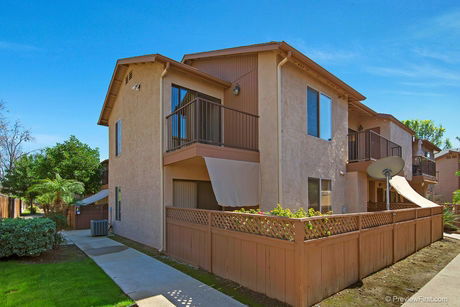 Front view of a two-story house with fenced patio.